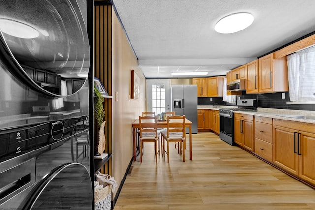 kitchen with a textured ceiling, sink, appliances with stainless steel finishes, and light hardwood / wood-style flooring