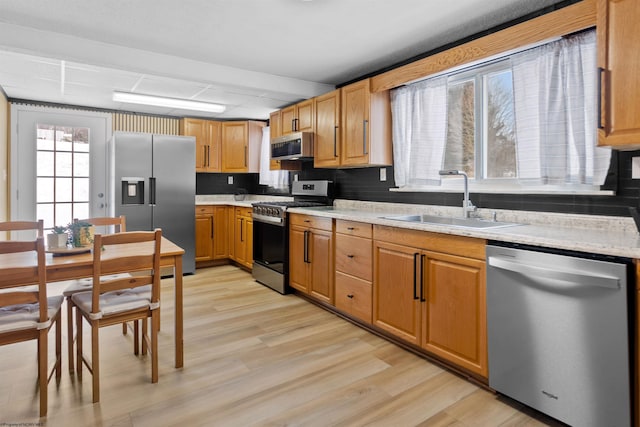 kitchen featuring appliances with stainless steel finishes, tasteful backsplash, light hardwood / wood-style flooring, and sink