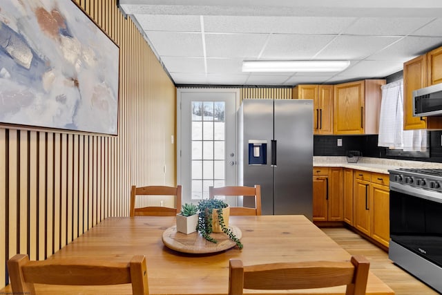 kitchen featuring backsplash, a drop ceiling, light hardwood / wood-style floors, and stainless steel appliances