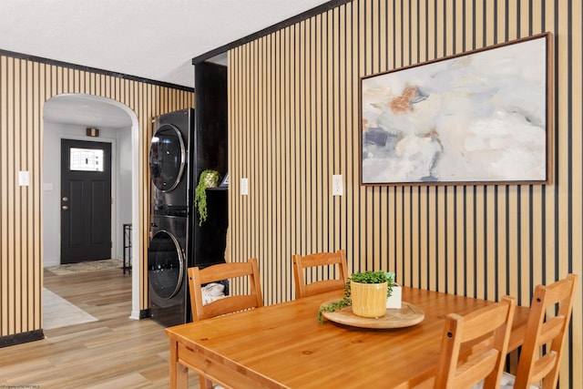 dining space featuring crown molding, stacked washer / dryer, and light hardwood / wood-style flooring