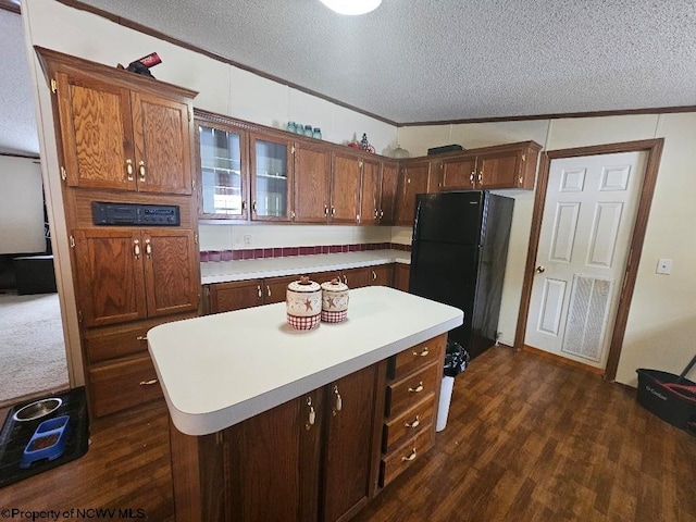 kitchen featuring a center island, dark hardwood / wood-style floors, crown molding, a textured ceiling, and black refrigerator