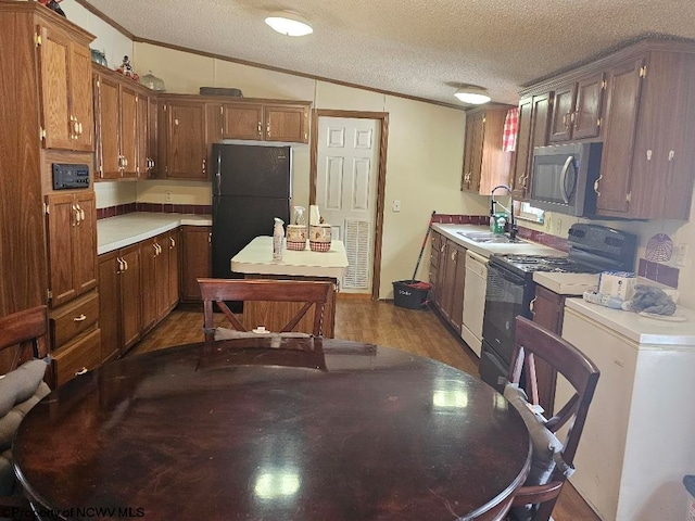 kitchen with lofted ceiling, black appliances, sink, a textured ceiling, and wood-type flooring