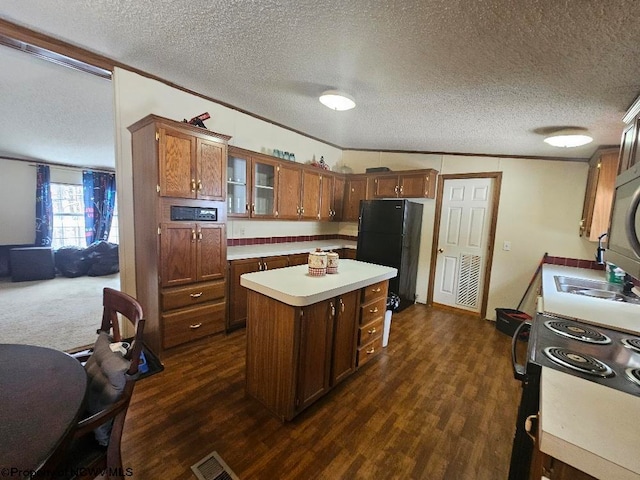 kitchen featuring black fridge, dark hardwood / wood-style flooring, crown molding, a textured ceiling, and a kitchen island