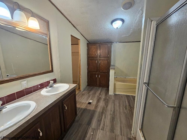 bathroom with separate shower and tub, hardwood / wood-style floors, a textured ceiling, vaulted ceiling, and vanity