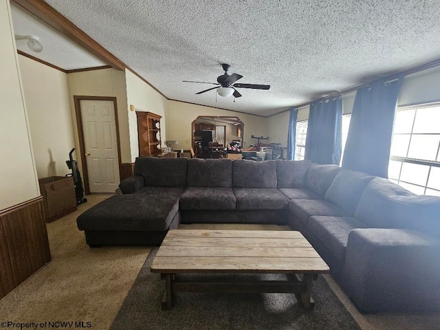 living room with ceiling fan, a textured ceiling, vaulted ceiling, wooden walls, and carpet