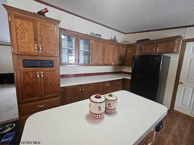 kitchen featuring dark hardwood / wood-style flooring, a textured ceiling, black fridge, and crown molding