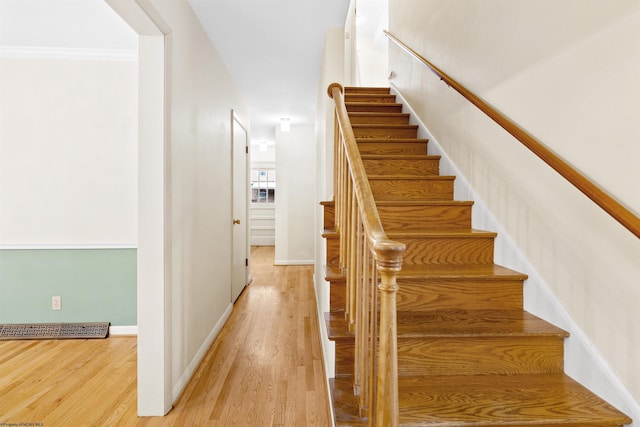 stairway with hardwood / wood-style flooring and crown molding