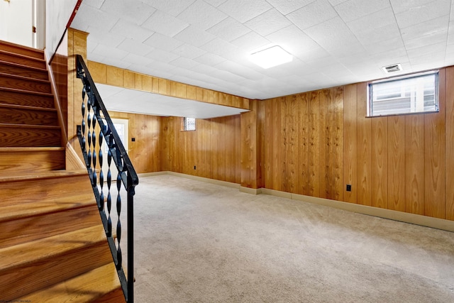 basement featuring carpet flooring and wood walls