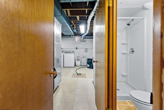 bathroom with toilet, a shower, and washer / clothes dryer