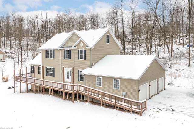 snow covered house featuring a garage