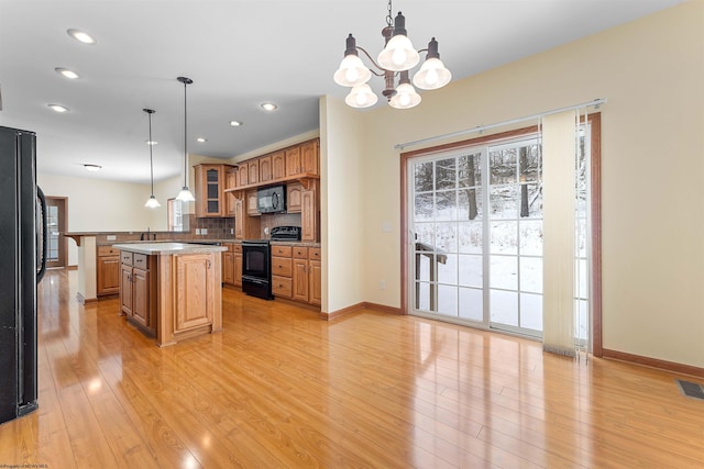 kitchen with backsplash, a kitchen island, hanging light fixtures, and black appliances