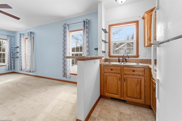 kitchen with light tile patterned floors, white fridge, ceiling fan, and sink