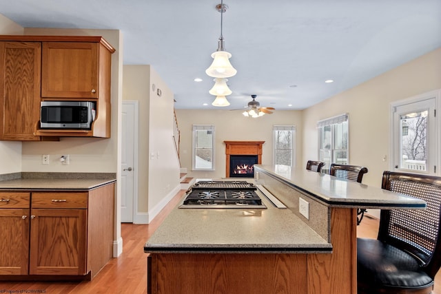 kitchen featuring a breakfast bar, decorative light fixtures, a center island, appliances with stainless steel finishes, and light hardwood / wood-style floors