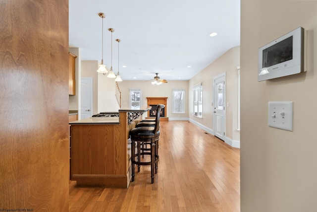 kitchen with stainless steel gas stovetop, decorative light fixtures, a kitchen bar, and light wood-type flooring