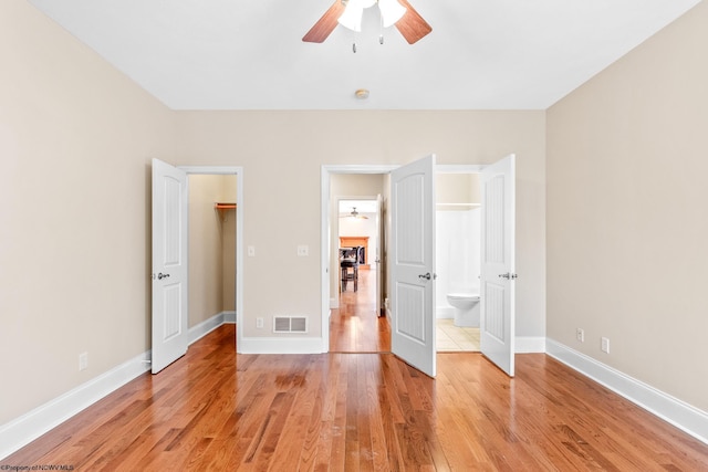 unfurnished bedroom featuring ceiling fan, a walk in closet, and light hardwood / wood-style floors