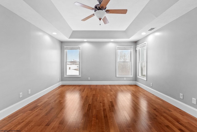 unfurnished room featuring ceiling fan, wood-type flooring, and a raised ceiling