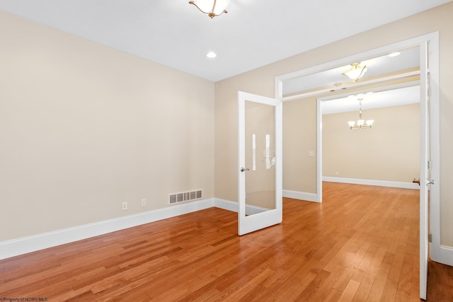 empty room with hardwood / wood-style flooring and a notable chandelier