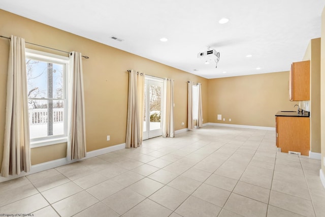 tiled spare room featuring plenty of natural light and sink