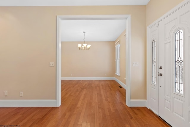 foyer with a healthy amount of sunlight, light hardwood / wood-style floors, and a notable chandelier