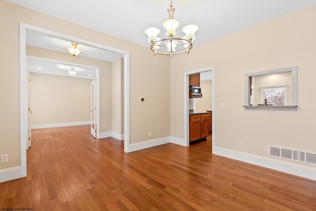 unfurnished dining area featuring an inviting chandelier and hardwood / wood-style floors