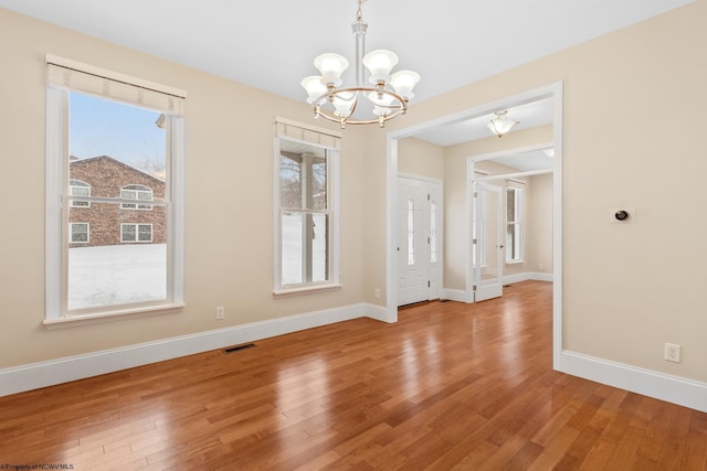 unfurnished dining area featuring hardwood / wood-style floors and a notable chandelier