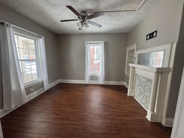 unfurnished living room featuring ceiling fan, dark hardwood / wood-style flooring, and a textured ceiling