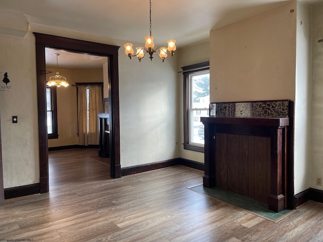 unfurnished dining area featuring wood-type flooring and a notable chandelier