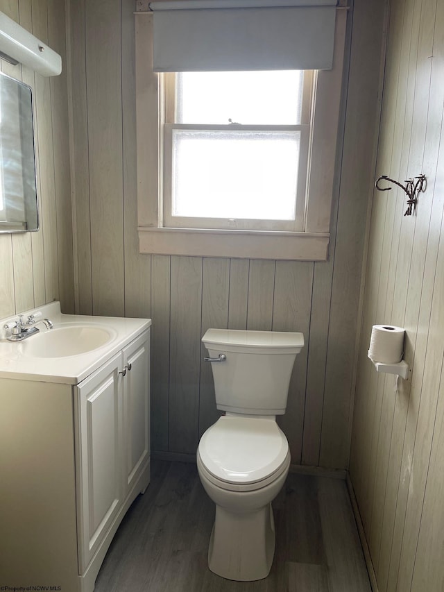 bathroom with vanity, toilet, wood-type flooring, and wooden walls