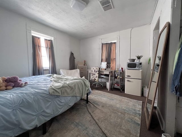 bedroom featuring dark carpet and a textured ceiling