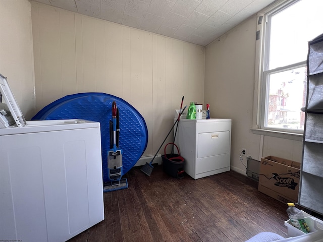 laundry area with wood walls, dark wood-type flooring, and independent washer and dryer