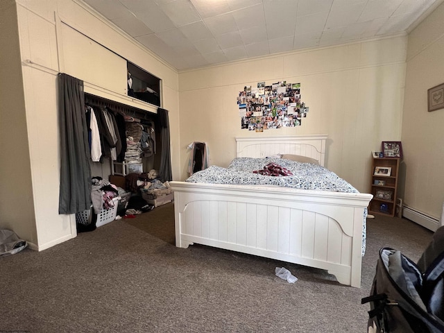 carpeted bedroom featuring a closet, ornamental molding, and a baseboard heating unit