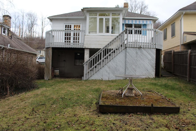 back of property featuring a wooden deck, a sunroom, and a yard