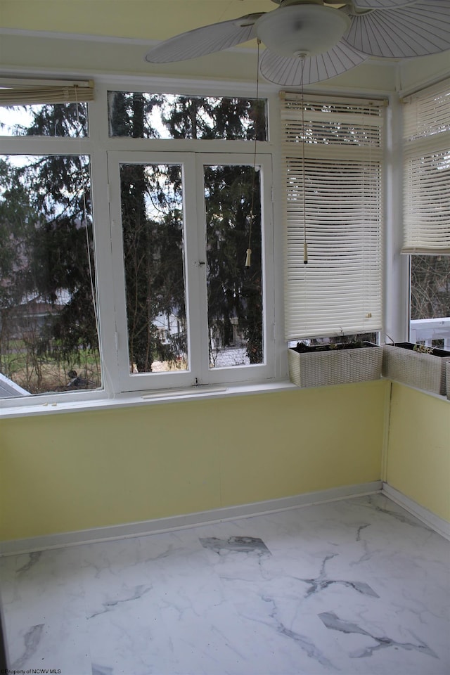 unfurnished sunroom featuring ceiling fan