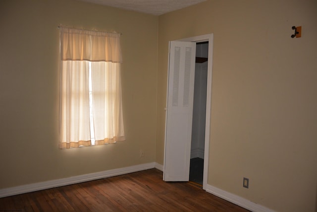 unfurnished bedroom with dark hardwood / wood-style floors and a closet