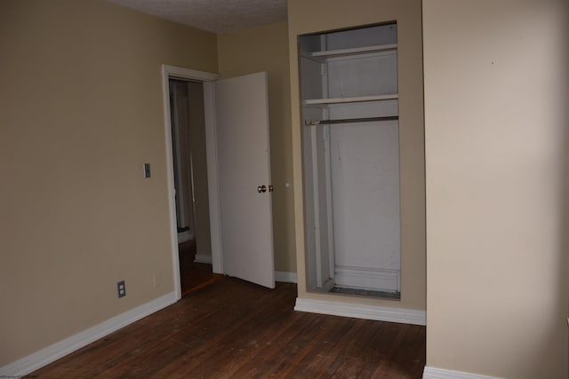 unfurnished bedroom featuring a textured ceiling, a closet, and dark hardwood / wood-style floors