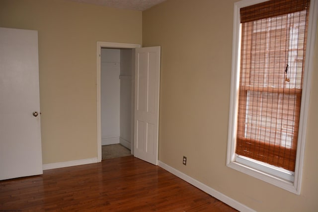 unfurnished bedroom with dark hardwood / wood-style flooring and a closet