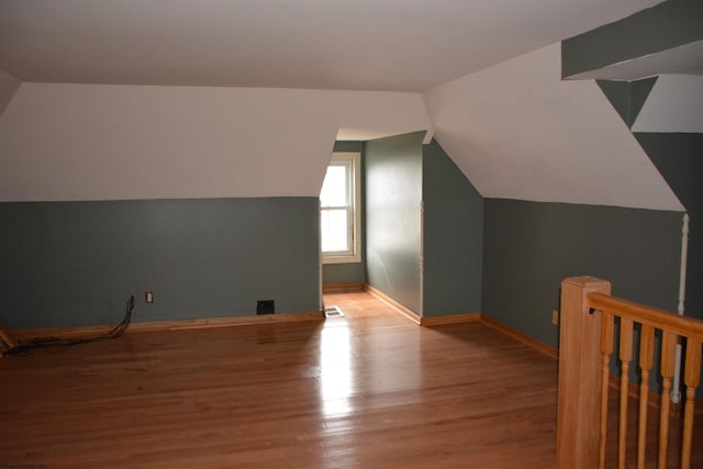 additional living space featuring vaulted ceiling and light hardwood / wood-style flooring