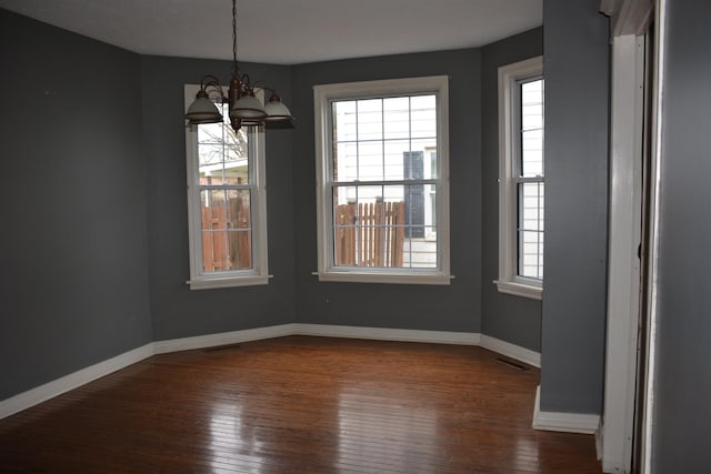 unfurnished dining area featuring dark hardwood / wood-style flooring and an inviting chandelier