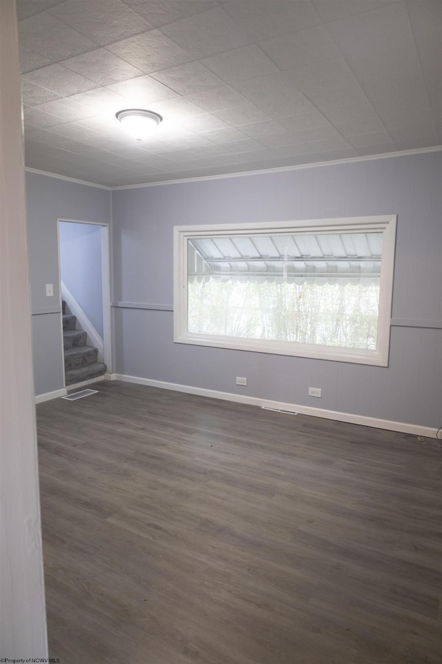 spare room featuring crown molding, dark wood-type flooring, and a healthy amount of sunlight