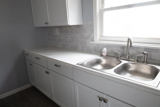 kitchen featuring white cabinets, tasteful backsplash, light stone countertops, and sink