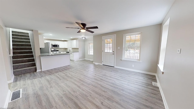 unfurnished living room with ceiling fan, a healthy amount of sunlight, and light hardwood / wood-style floors