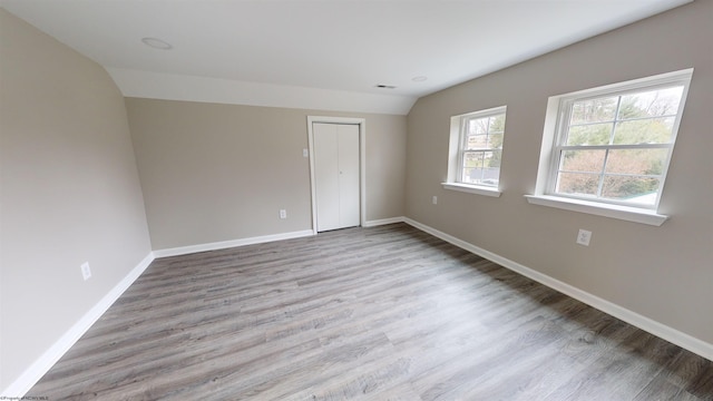 unfurnished bedroom with light hardwood / wood-style floors, a closet, and lofted ceiling