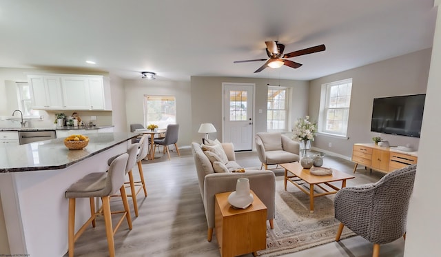 living room with light hardwood / wood-style flooring, ceiling fan, and sink