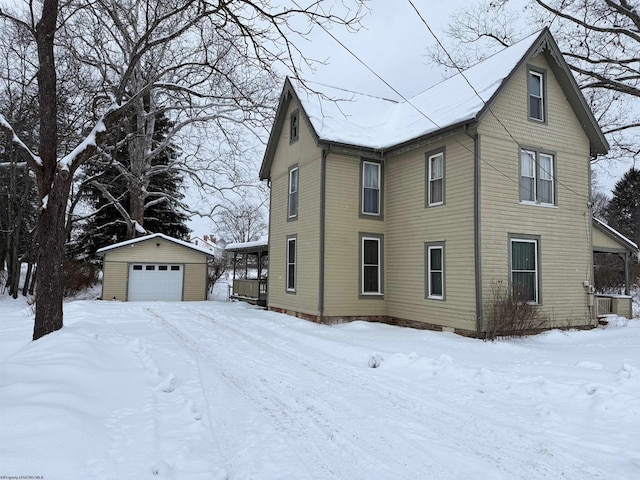 view of snow covered exterior featuring an outbuilding and a garage