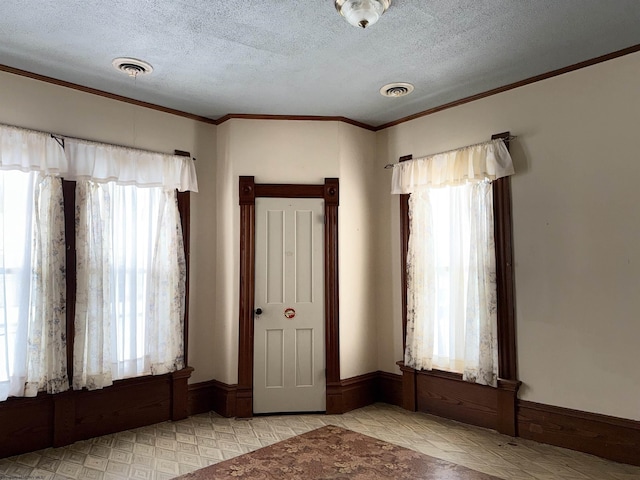 foyer entrance featuring a textured ceiling and crown molding