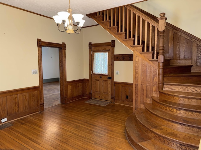 interior space featuring crown molding, wood-type flooring, and an inviting chandelier