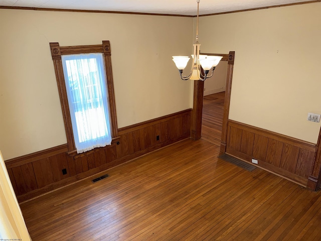 unfurnished room with a chandelier, dark wood-type flooring, and crown molding