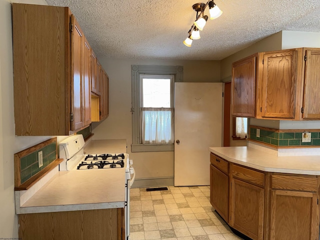 kitchen with a textured ceiling, white range with gas cooktop, and backsplash