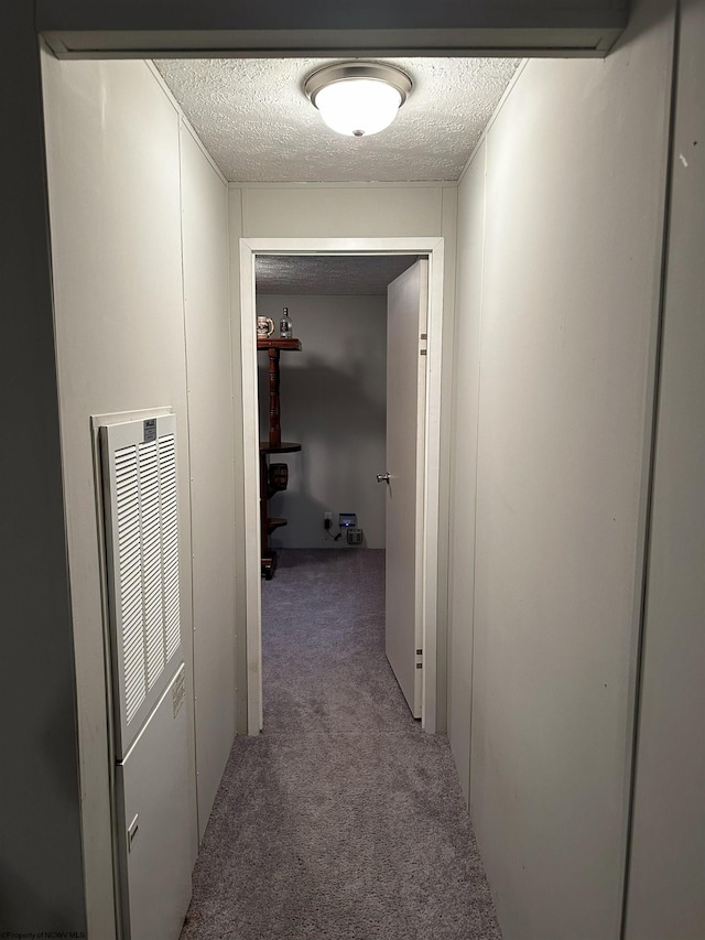 hallway with carpet floors and a textured ceiling