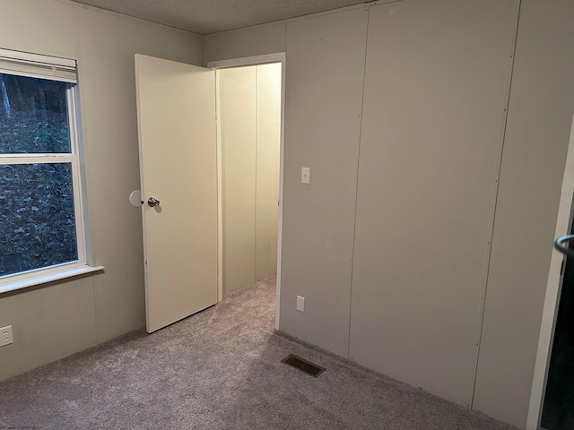 unfurnished bedroom featuring a textured ceiling and light colored carpet